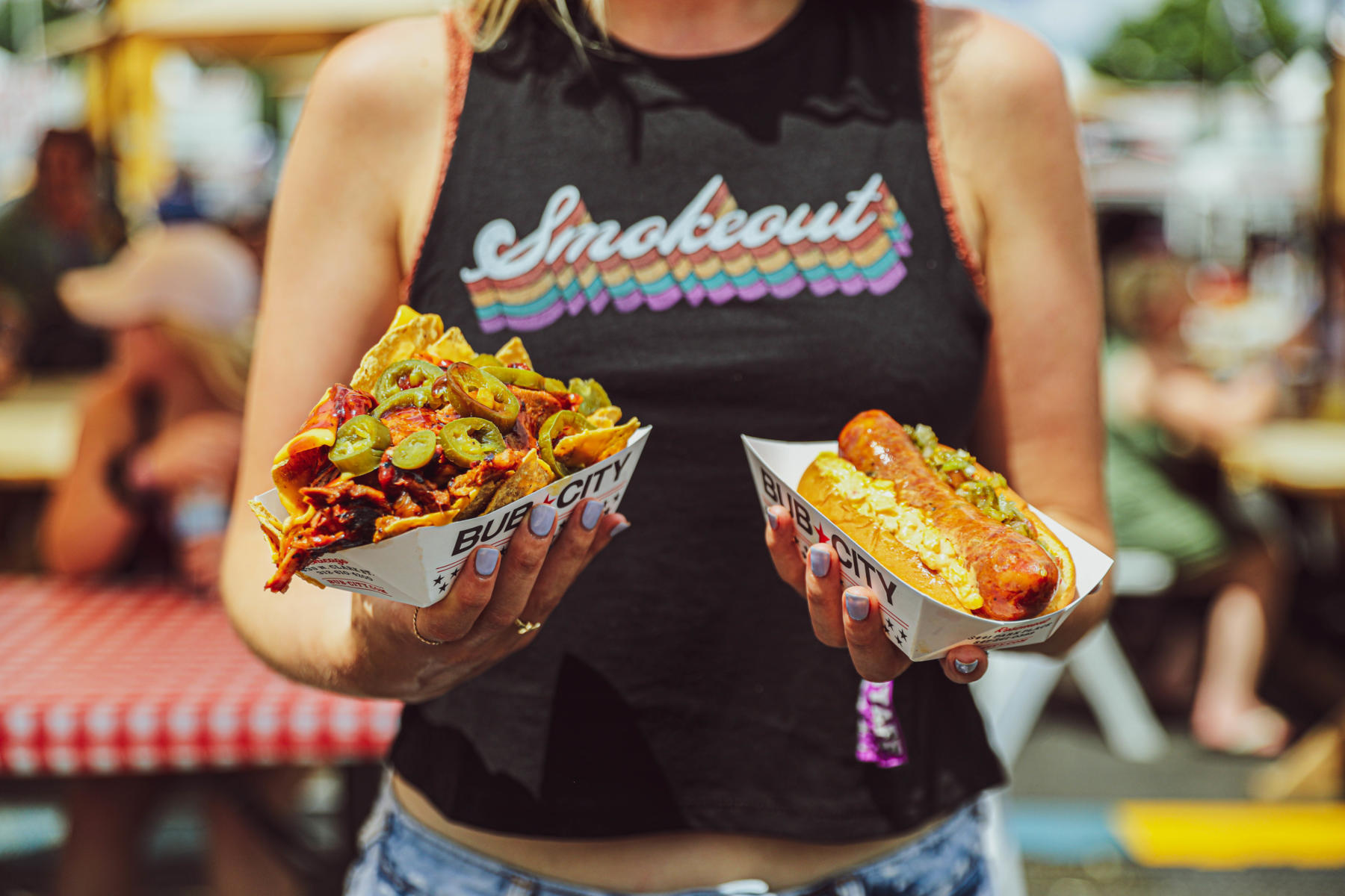 A woman holds BBQ dishes at Windy City Smokeout